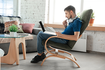 Image showing Young focused man studying at home during online courses or free information by hisself