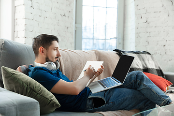 Image showing Young focused man studying at home during online courses or free information by hisself