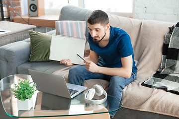 Image showing Young focused man studying at home during online courses or free information by hisself