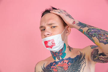 Image showing Young man with freaky appearance on pink background wearing face mask with coronavirus model