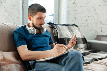 Image showing Young focused man studying at home during online courses or free information by hisself