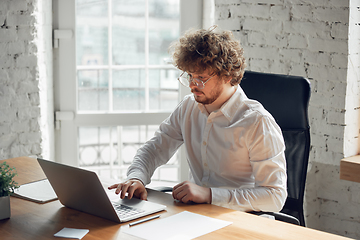 Image showing Caucasian young man in business attire working in office, job, online studying