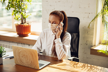 Image showing Woman working in office alone during coronavirus or COVID-19 quarantine, wearing face mask