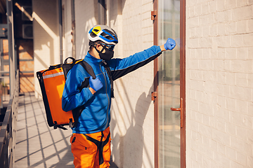 Image showing Contacless delivery service during quarantine. Man delivers food and shopping bags during isolation