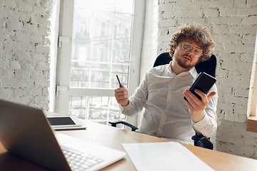 Image showing Caucasian young man in business attire working in office, job, online studying