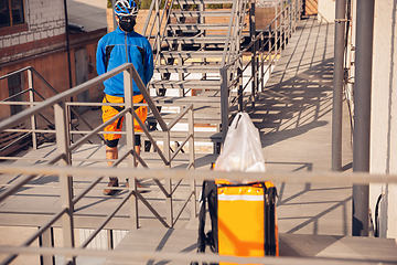 Image showing Contacless delivery service during quarantine. Man delivers food and shopping bags during isolation