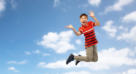 Image showing happy smiling young boy jumping in air over sky