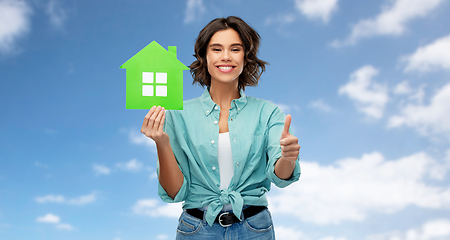 Image showing smiling woman with green house showing thumbs up