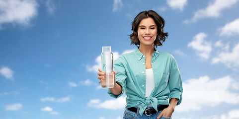 Image showing smiling young woman holding water in glass bottle