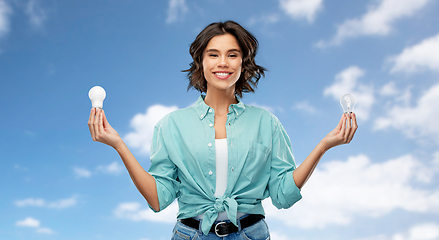 Image showing smiling woman comparing different light bulbs