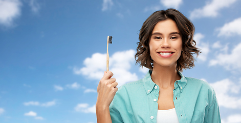 Image showing smiling young woman with wooden toothbrush