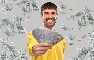 Image showing smiling young man in yellow sweatshirt with money