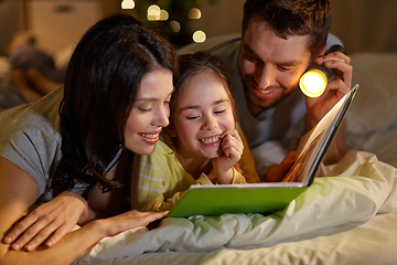 Image showing happy family reading book in bed at night at home