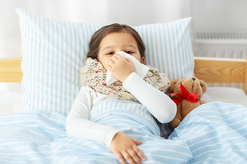 Image showing sick girl lying in bed and blowing nose at home