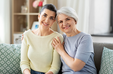 Image showing senior mother with adult daughter hugging at home