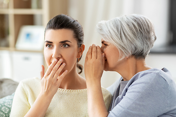 Image showing senior mother whispering secret to adult daughter