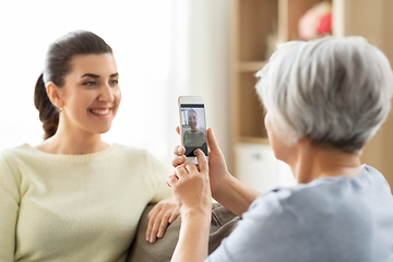 Image showing senior mother photographing adult daughter at home