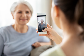 Image showing adult daughter photographing senior mother at home