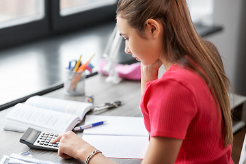 Image showing student girl counting on calculator at home