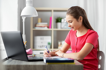 Image showing teenage student girl writing to notebook at home