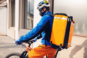 Image showing Contacless delivery service during quarantine. Man delivers food and shopping bags during isolation