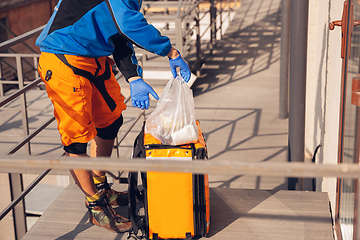 Image showing Contacless delivery service during quarantine. Man delivers food and shopping bags during isolation