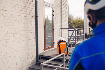 Image showing Contacless delivery service during quarantine. Man delivers food and shopping bags during isolation