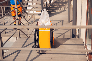 Image showing Contacless delivery service during quarantine. Man delivers food and shopping bags during isolation