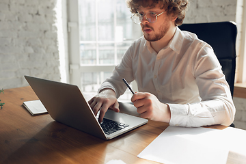 Image showing Caucasian young man in business attire working in office, job, online studying