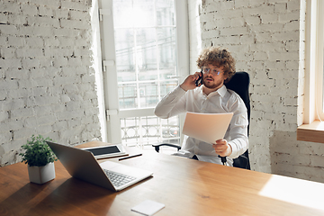 Image showing Caucasian young man in business attire working in office, job, online studying