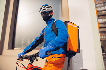 Image showing Contacless delivery service during quarantine. Man delivers food and shopping bags during isolation