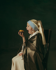 Image showing Medieval little girl as a lady with a pearl earring on dark studio background. Concept of comparison of eras, childhood. Stylish creative design, art vision, new look of artwork.