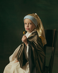 Image showing Medieval little girl as a lady with a pearl earring on dark studio background. Concept of comparison of eras, childhood. Stylish creative design, art vision, new look of artwork.