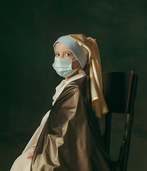 Image showing Medieval little girl as a lady with a pearl earring on dark studio background. Concept of comparison of eras, childhood. Stylish creative design, art vision, new look of artwork.