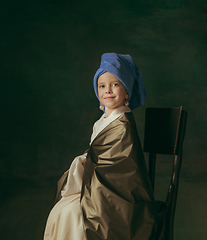 Image showing Medieval little girl as a lady with a pearl earring on dark studio background. Concept of comparison of eras, childhood. Stylish creative design, art vision, new look of artwork.