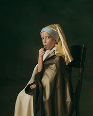 Image showing Medieval little girl as a lady with a pearl earring on dark studio background. Concept of comparison of eras, childhood. Stylish creative design, art vision, new look of artwork.