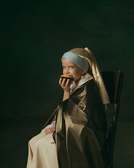 Image showing Medieval little girl as a lady with a pearl earring on dark studio background. Concept of comparison of eras, childhood. Stylish creative design, art vision, new look of artwork.