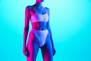 Image showing Beautiful female body on blue background in purple neon light. Beauty, cosmetics, spa, depilation, diet and treatment, fitness concept.