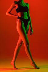 Image showing Beautiful female model on orange background in neon light. Beauty, cosmetics, spa, depilation, diet and treatment, fitness concept.