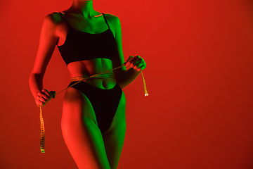 Image showing Beautiful female model on orange background in neon light. Beauty, cosmetics, spa, depilation, diet and treatment, fitness concept.