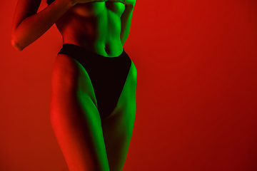 Image showing Beautiful female model on orange background in neon light. Beauty, cosmetics, spa, depilation, diet and treatment, fitness concept.