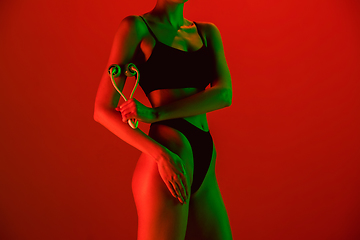 Image showing Beautiful female model on orange background in neon light. Beauty, cosmetics, spa, depilation, diet and treatment, fitness concept.
