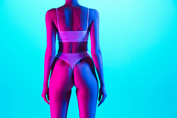 Image showing Beautiful female body on blue background in purple neon light. Beauty, cosmetics, spa, depilation, diet and treatment, fitness concept.