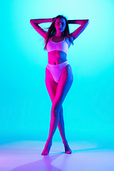 Image showing Beautiful female body on blue background in purple neon light. Beauty, cosmetics, spa, depilation, diet and treatment, fitness concept.