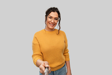 Image showing smiling woman taking picture with selfie stick