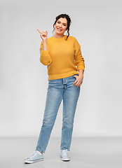 Image showing happy smiling young woman pointing finger up