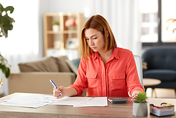 Image showing woman with calculator and papers working at home