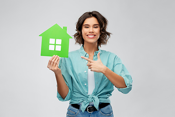 Image showing smiling young woman showing green house