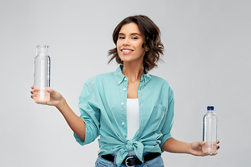 Image showing smiling young woman comparing bottles of water