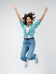 Image showing happy young woman jumping over grey background